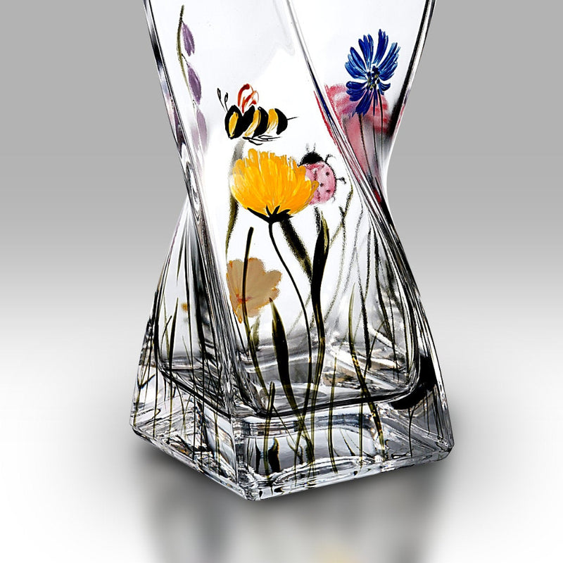 Decorative glass vase with floral and bee design on a gray background